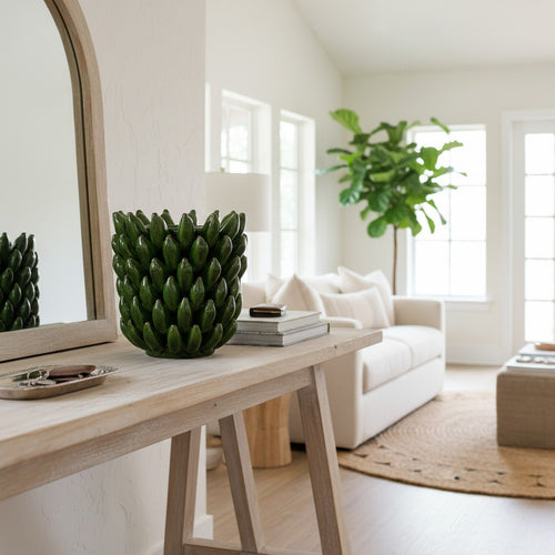 Banana Vase styled on a light wood console in a bright modern living room — sculptural green ceramic vase with a layered botanical form, HMT Home