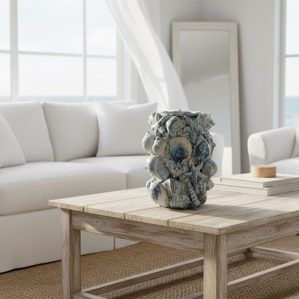 Beach Shell Vase styled on a driftwood coffee table in a bright coastal living room — blue and cream shell-encrusted ceramic vase, HMT Home