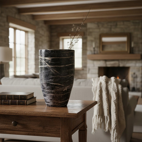 Black Wood Vase styled with dried branches on a wooden side table beside a stone fireplace — tapered ceramic vase in charred wood grain with a white rim, HMT Home