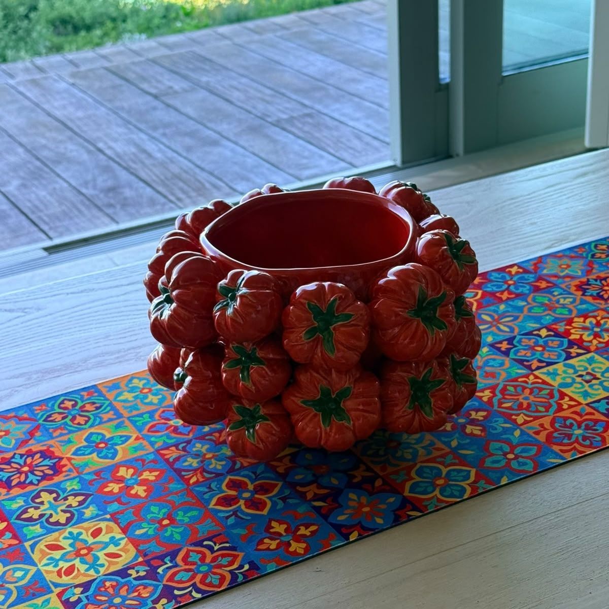 Rosa Tomato Pot styled on a colourful patterned table runner, showing its glossy red interior — ceramic pot covered in sculpted tomatoes, HMT Home