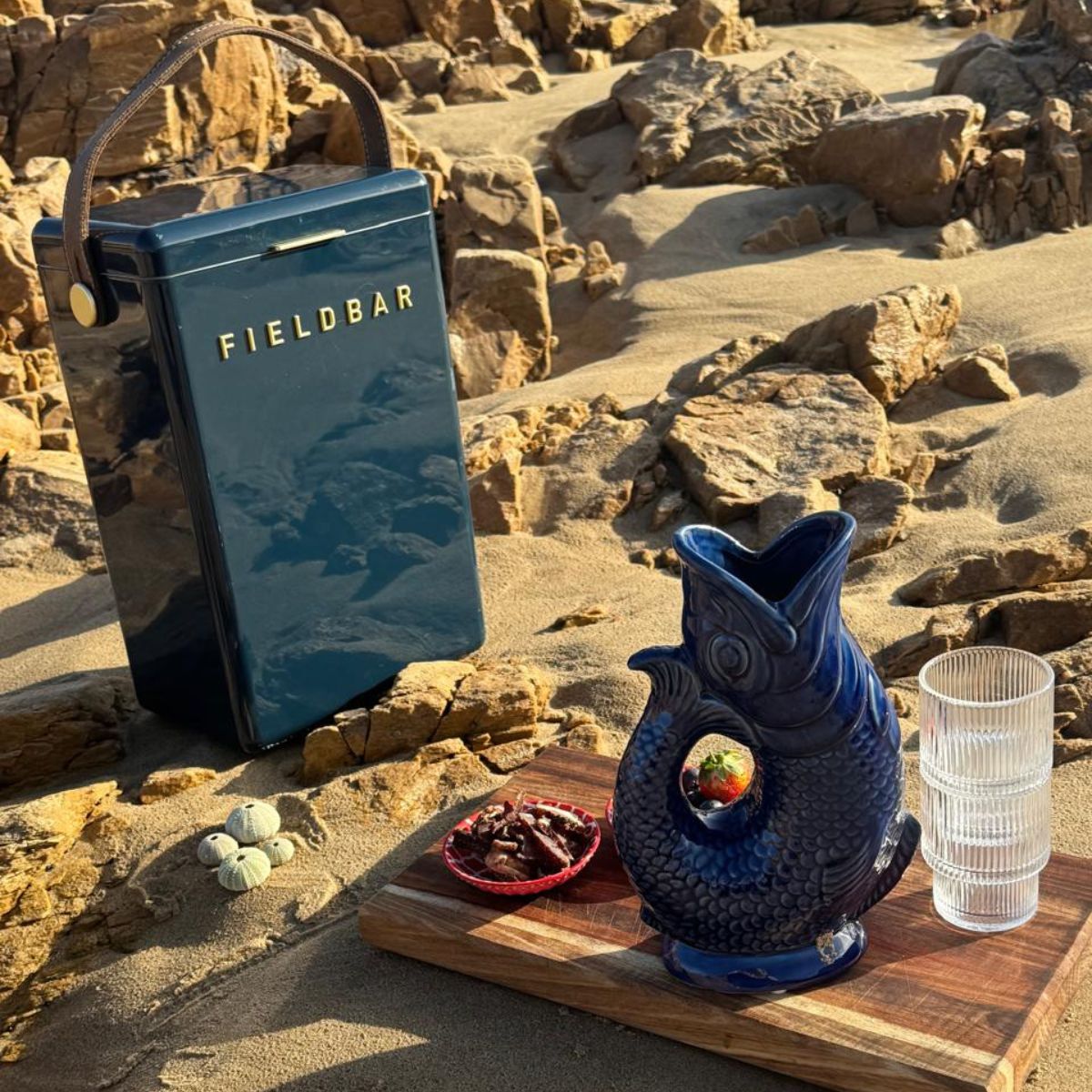 Koi Fish Jug styled on a wooden board at the beach in late afternoon light — deep cobalt fish-shaped ceramic jug, HMT Home