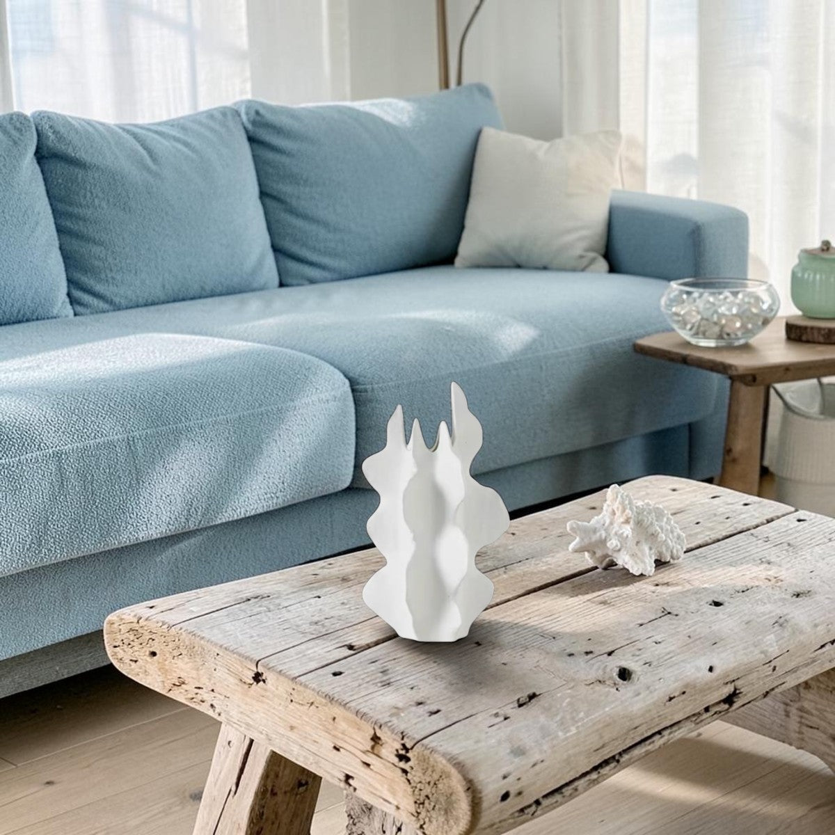 Wave Vase styled on a rustic wood coffee table beside a coral piece, pale blue sofa and sheer curtains behind, HMT Home